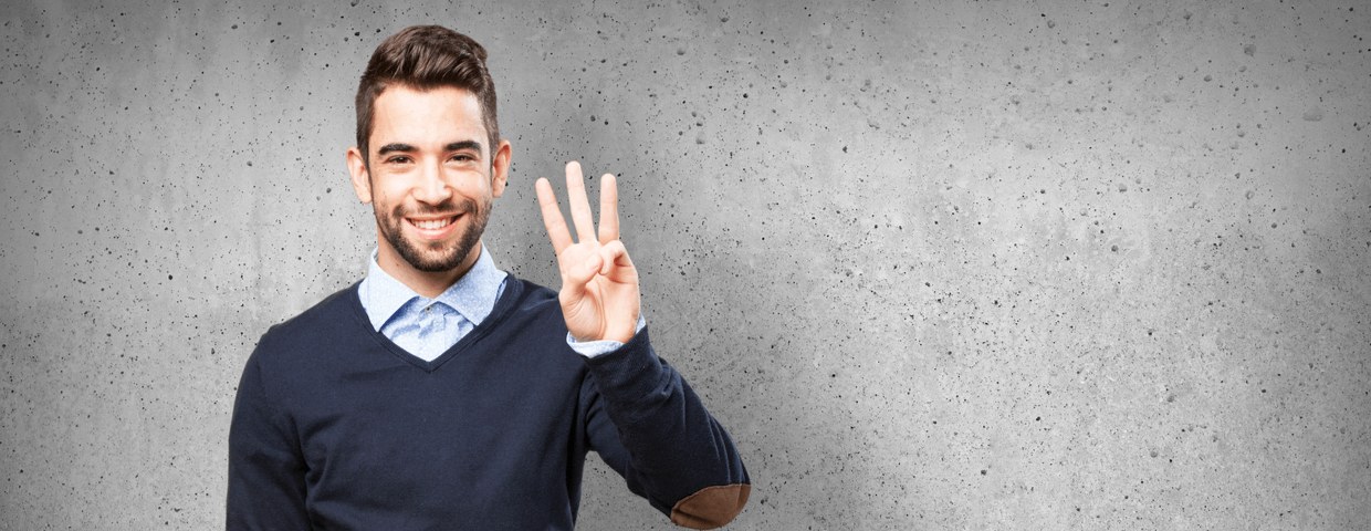 Young man smiling, holding up three fingers.