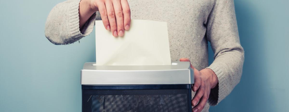 Man is shredding a piece of paper in a paper shredder